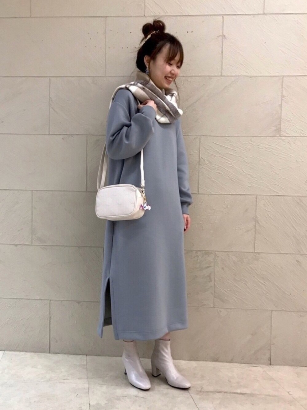 グレー系のワンピース、ベージュ系のブーツ、ホワイト系のショルダーバッグを着用したレディースの秋コーディネートの1枚目の写真