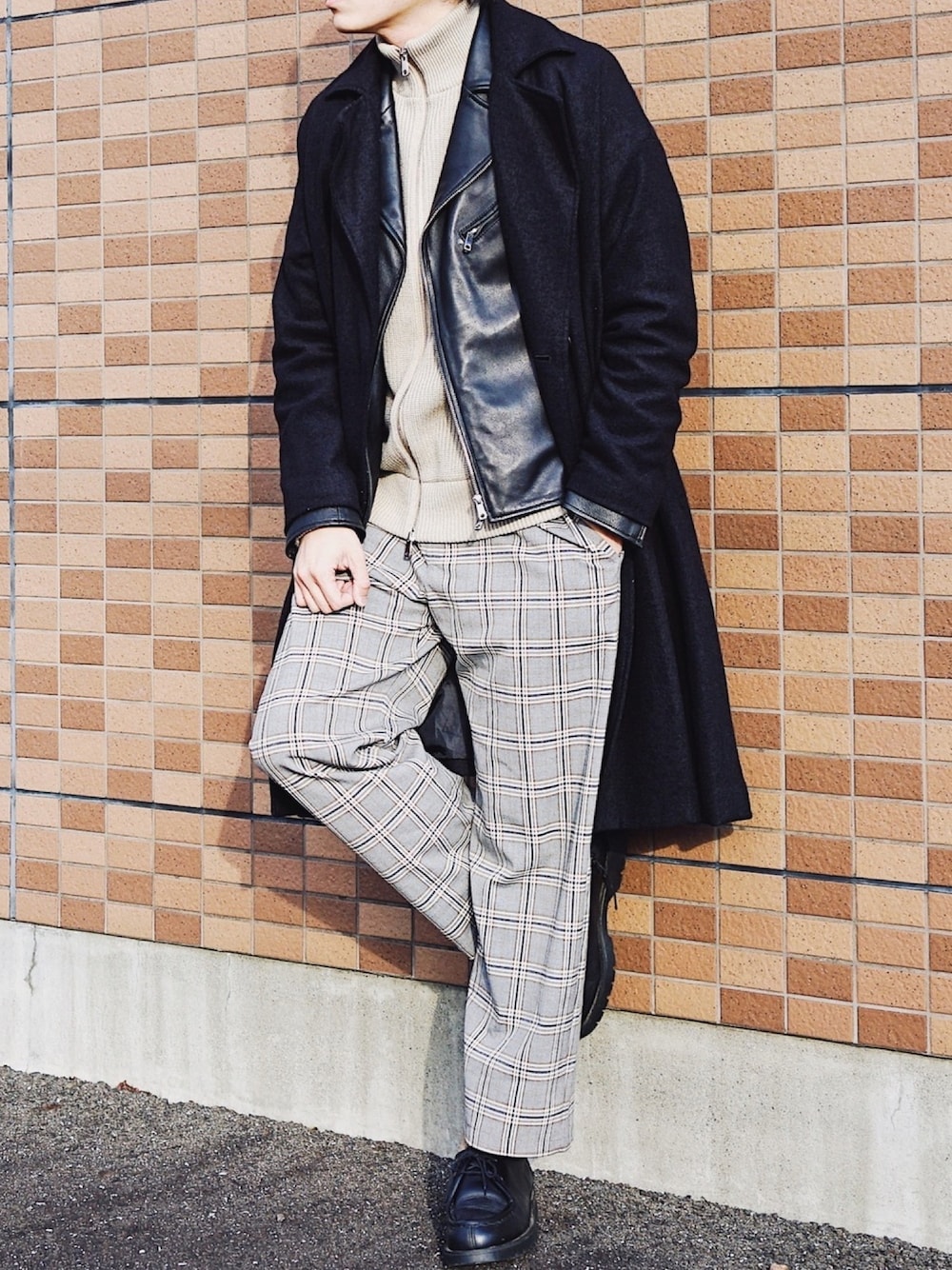 ブラック系のチェスターコート、ブラック系のライダースジャケット、ベージュ系のニット/セーターを着用したメンズの冬コーディネートの1枚目の写真