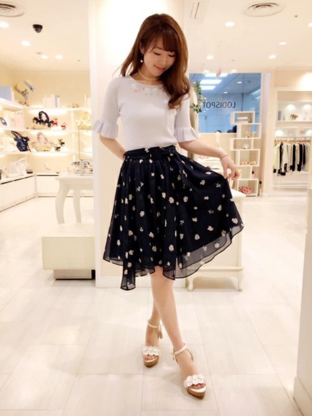 ブルー系のニット/セーター、ブルー系のスカート、ホワイト系のサンダルを着用したレディースの春コーディネートの1枚目の写真