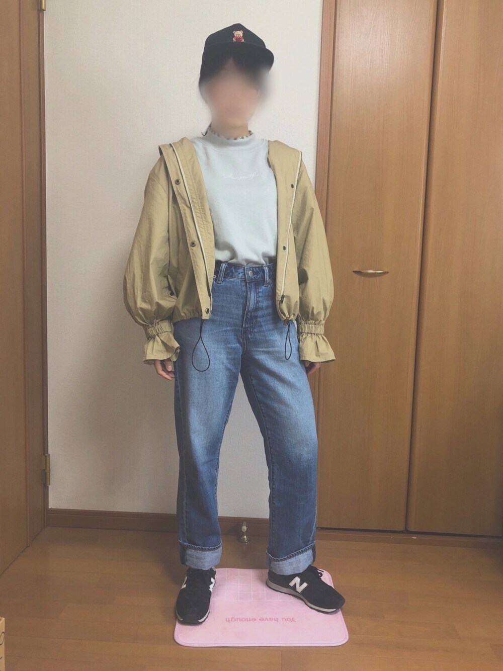 ブルー系のデニムパンツ、ベージュ系のマウンテンパーカー、ブラック系のスニーカーを着用したレディースの春コーディネートの1枚目の写真