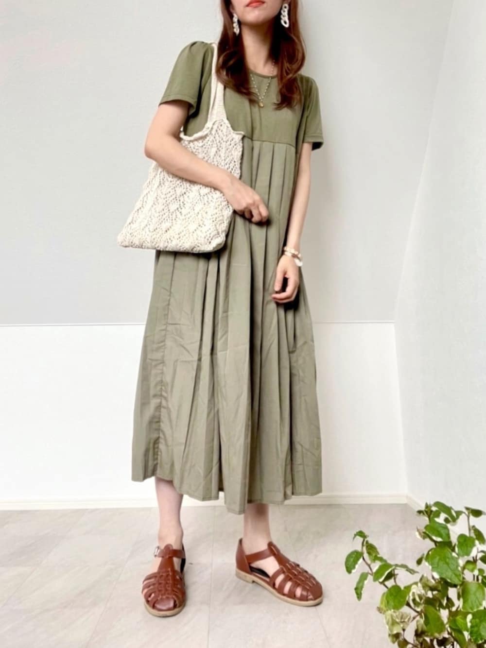 グリーン系のワンピース、ホワイト系のトートバッグ、ゴールド系のネックレスを着用したレディースの夏コーディネートの1枚目の写真