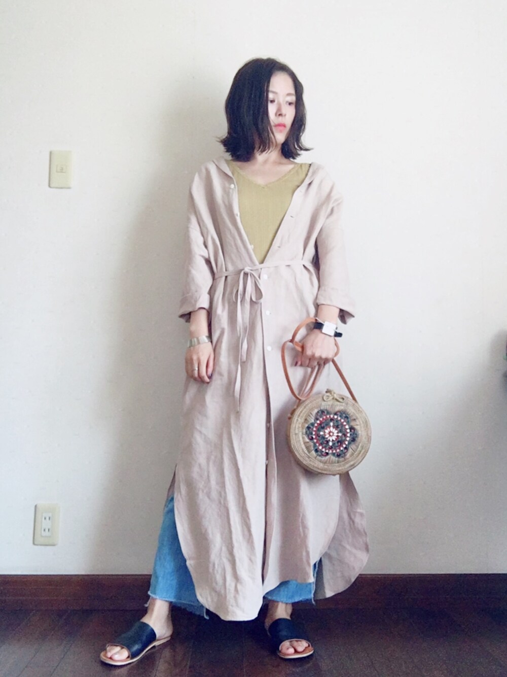 ベージュ系のシャツワンピース、イエロー系のキャミソール、ブルー系のデニムパンツを着用したレディースの夏コーディネートの1枚目の写真