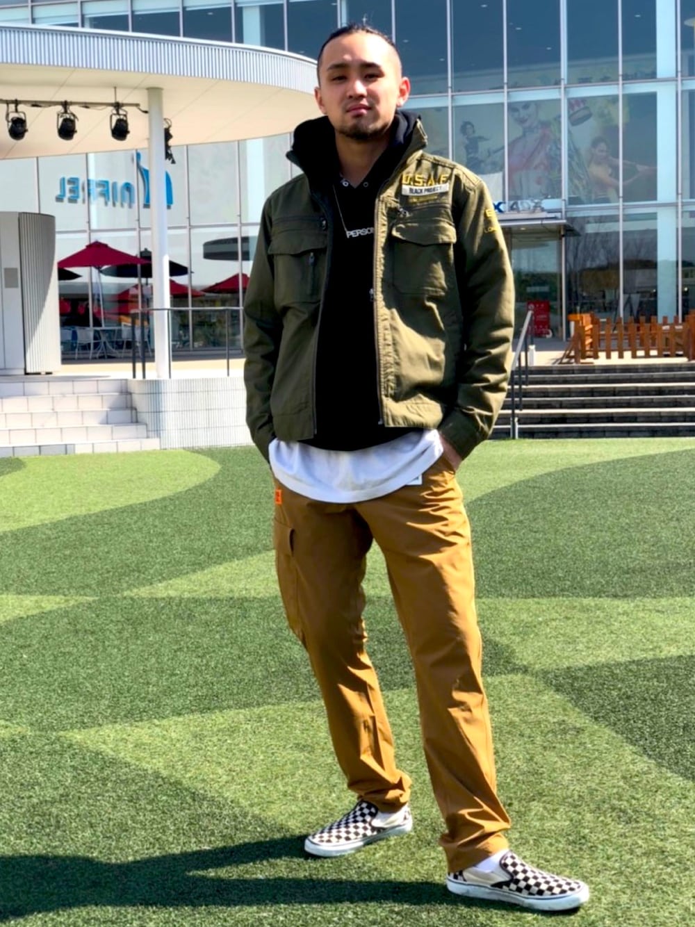 グリーン系のミリタリージャケット、ベージュ系のカーゴパンツを着用したメンズの春コーディネートの1枚目の写真