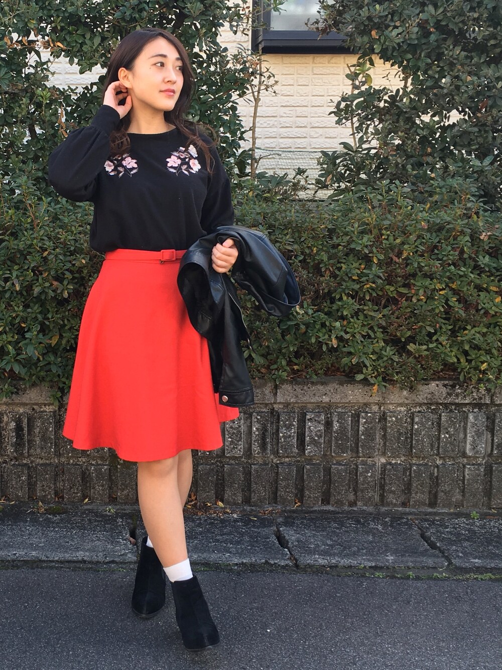 レッド系のスカート、ブラック系のトップスを着用したレディースの冬コーディネートの1枚目の写真