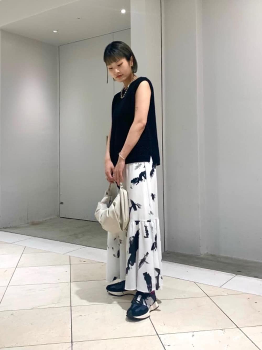 ブラック系のスニーカー、ブラック系のニット/セーター、ブラック系のスカートを着用したレディースの夏コーディネートの1枚目の写真
