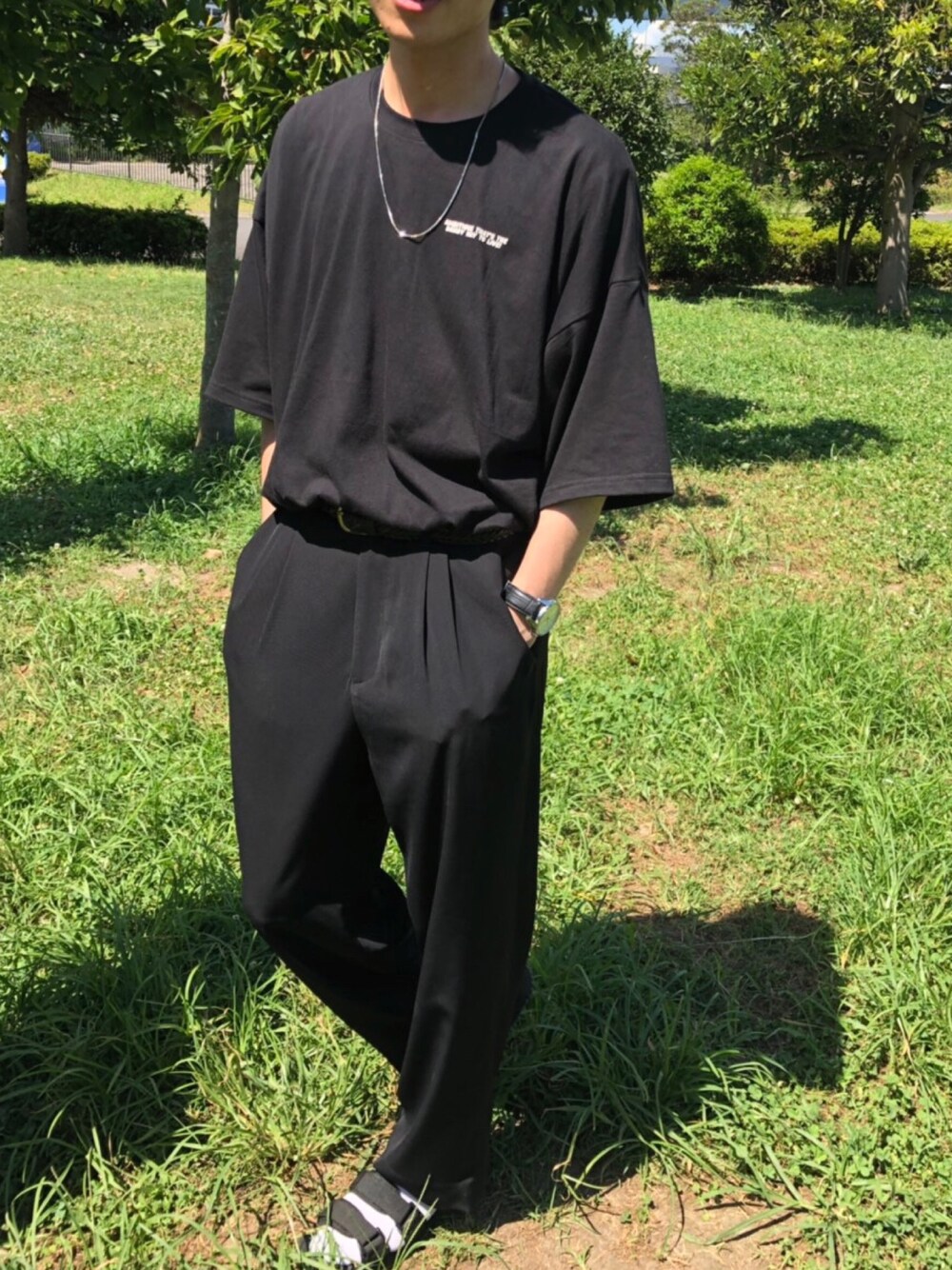 ブラック系のTシャツ/カットソー、ブラック系のスラックス、ブラック系のサンダルを着用したメンズの夏コーディネートの1枚目の写真