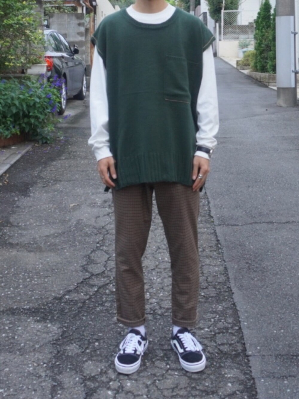 グリーン系のベスト、ホワイト系のTシャツ/カットソー、ブラウン系のスラックスを着用したメンズの秋コーディネートの1枚目の写真