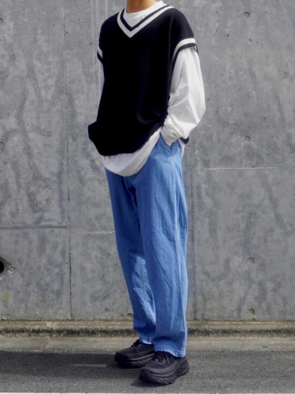 ブラック系のニット/セーター、ホワイト系のTシャツ/カットソー、ブラック系のスニーカーを着用したメンズの秋コーディネートの1枚目の写真