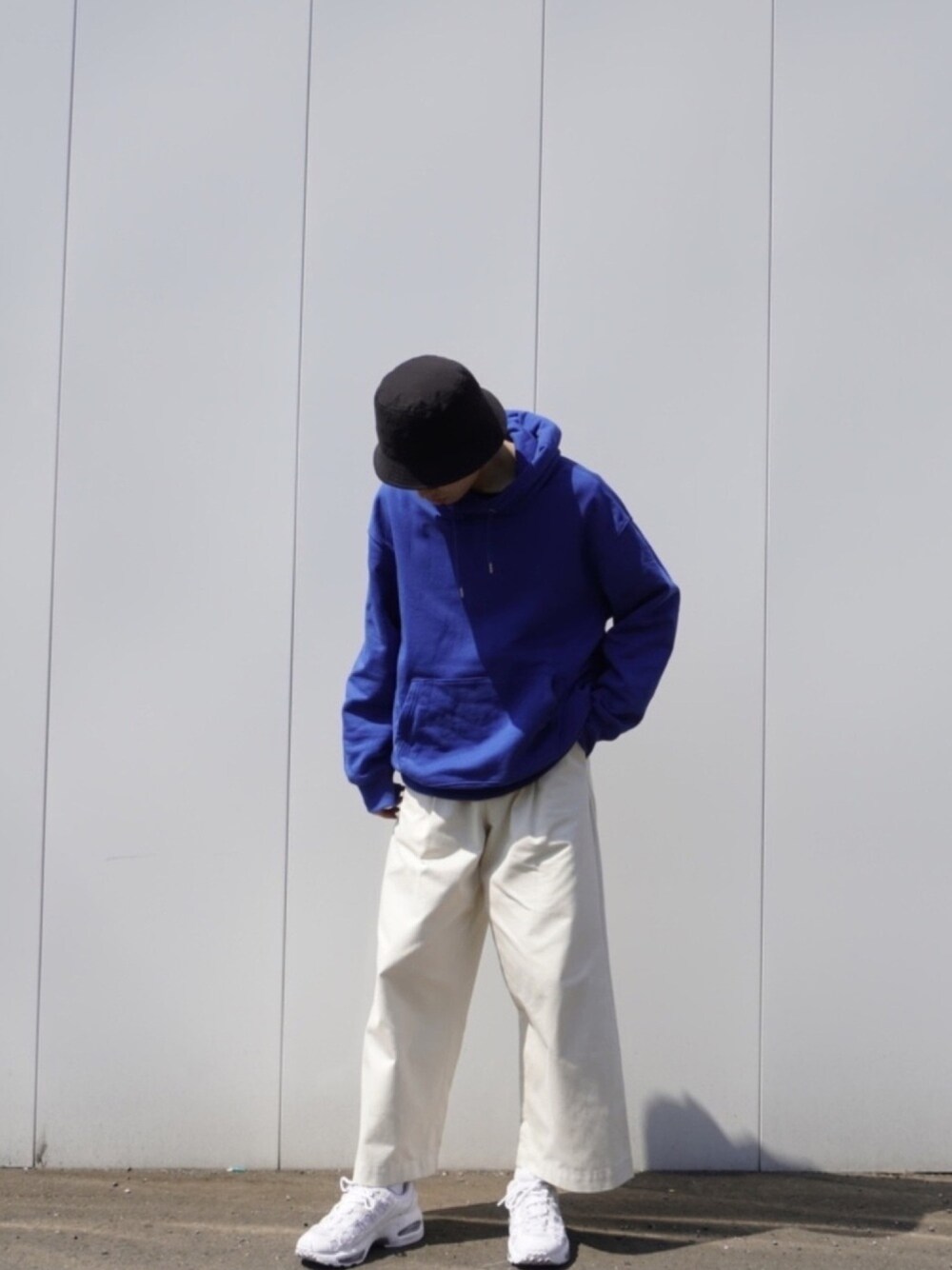 ブルー系のパーカー、ホワイト系のパンツ、ホワイト系のシューズを着用したメンズの春コーディネートの1枚目の写真