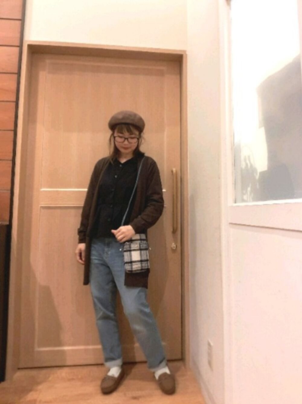 ブラウン系のカーディガン/ボレロ、ブラック系のバッグ、ブルー系のデニムパンツを着用したレディースの秋コーディネートの1枚目の写真