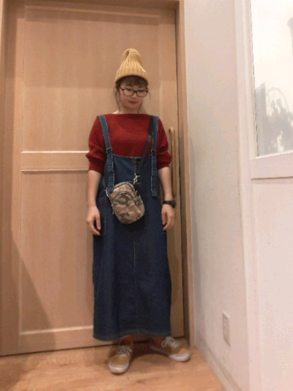 レッド系のニット/セーター、ブルー系のワンピース、ベージュ系のショルダーバッグを着用したレディースの秋コーディネートの1枚目の写真