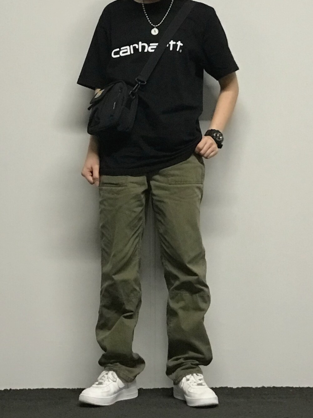 グリーン系のカーゴパンツ、ブラック系のTシャツ/カットソー、ブラック系のショルダーバッグを着用したレディースの秋コーディネートの1枚目の写真