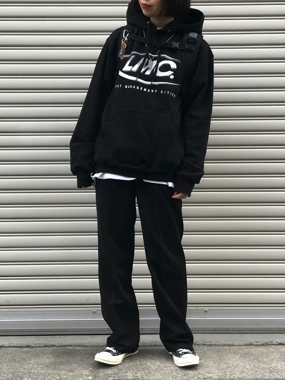 ブラック系のパーカー、ブラック系のスラックス、ブラック系のスニーカーを着用したレディースの秋コーディネートの1枚目の写真