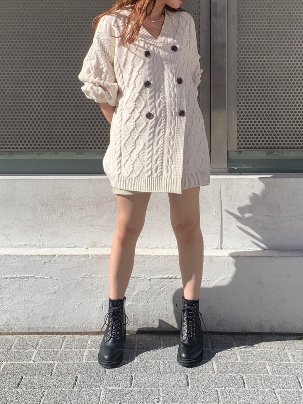 ホワイト系のニット/セーター、ホワイト系のスカート、ブラック系のブーツを着用したレディースの秋コーディネートの1枚目の写真