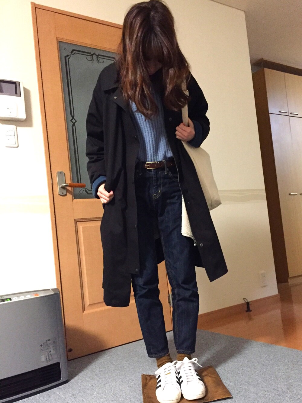 ブルー系のニット/セーター、ブラック系のその他アウター、ブラック系のスニーカーを着用したレディースの冬コーディネートの1枚目の写真