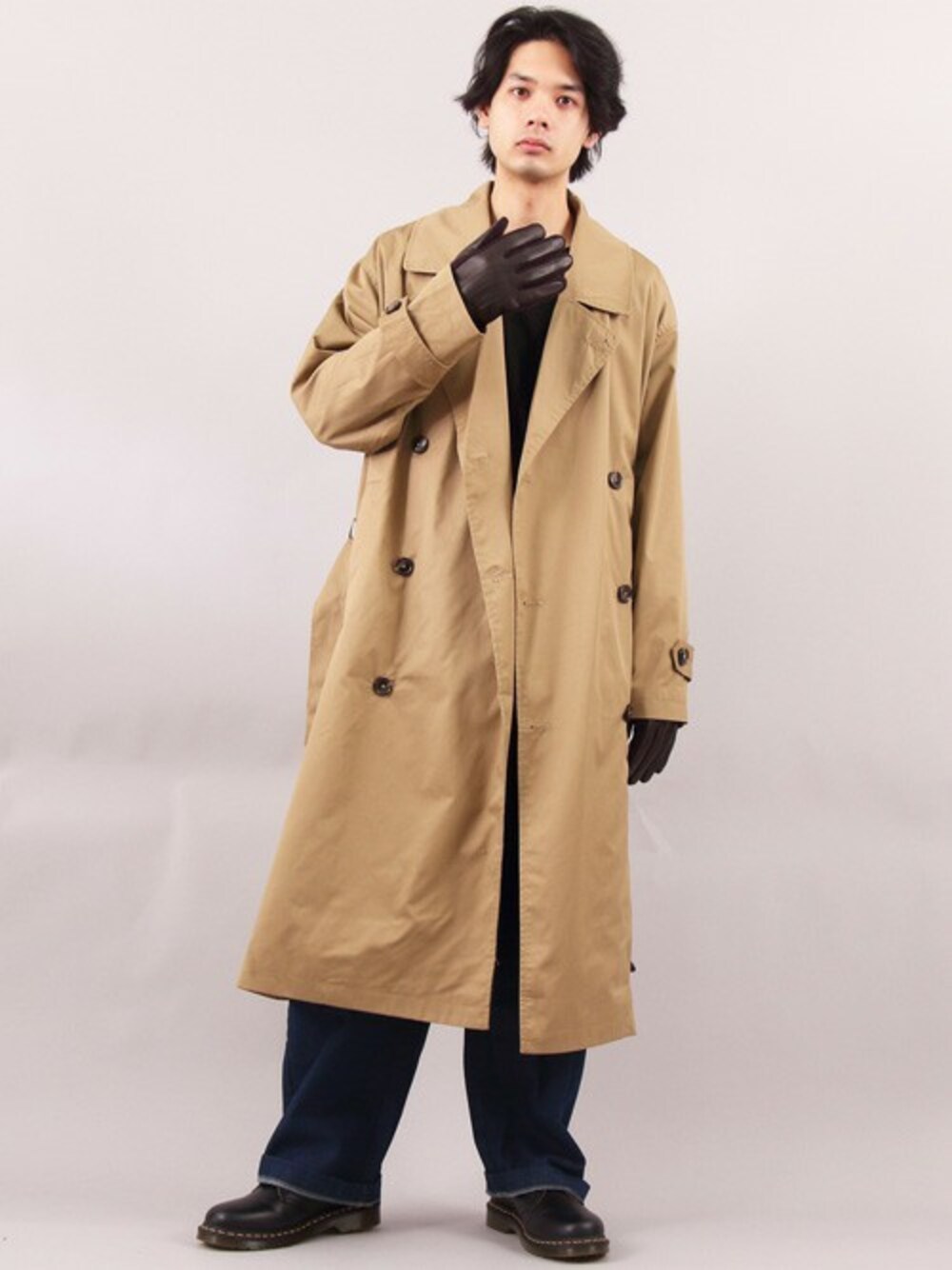 ベージュ系のトレンチコート、ブラック系のTシャツ/カットソー、ブルー系のデニムパンツを着用したメンズの春コーディネートの1枚目の写真