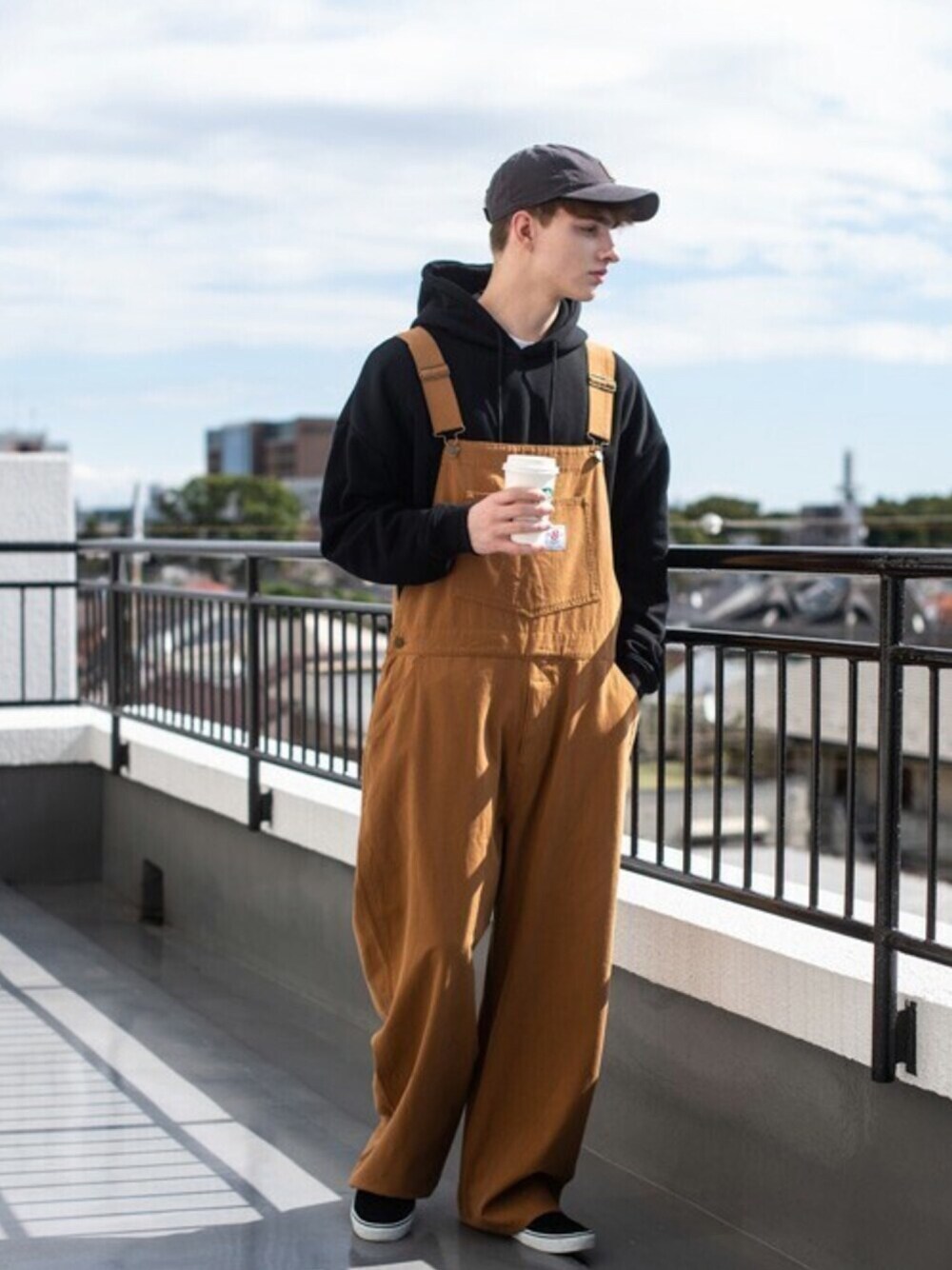 ブラック系のパーカー、ホワイト系のTシャツ/カットソー、ブラウン系のサロペット/オーバーオールを着用したメンズの秋コーディネートの1枚目の写真