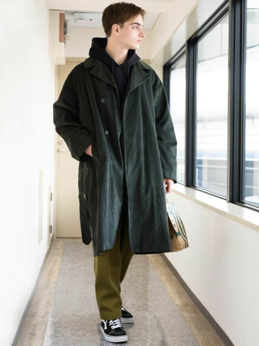 グリーン系のトレンチコート、ブラック系のパーカー、ホワイト系のTシャツ/カットソーを着用したメンズの冬コーディネートの1枚目の写真
