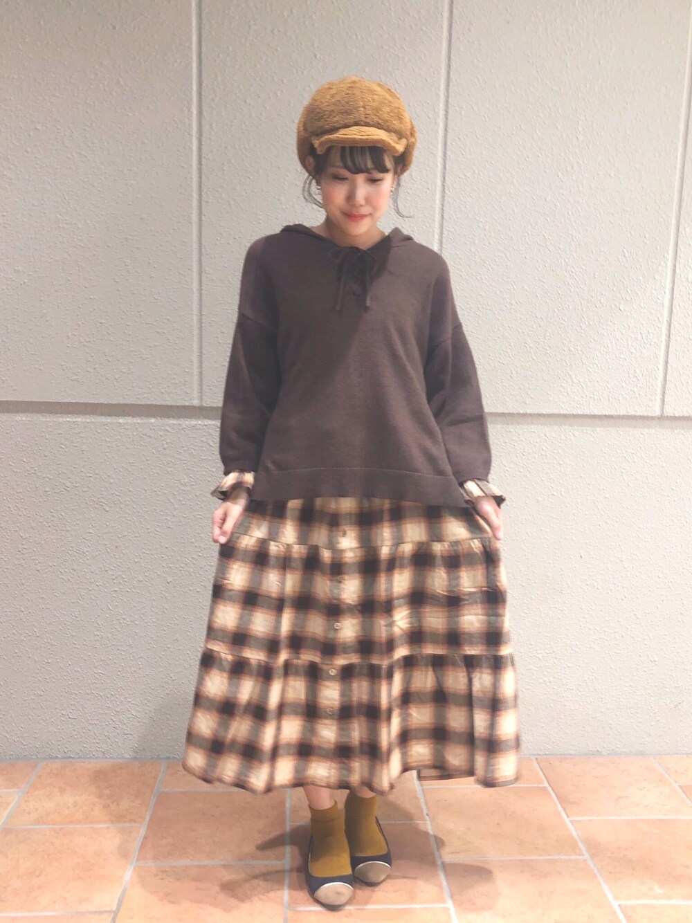 ブラウン系のニット/セーター、ブラウン系のワンピース、イエロー系のキャップを着用したレディースの秋コーディネートの1枚目の写真