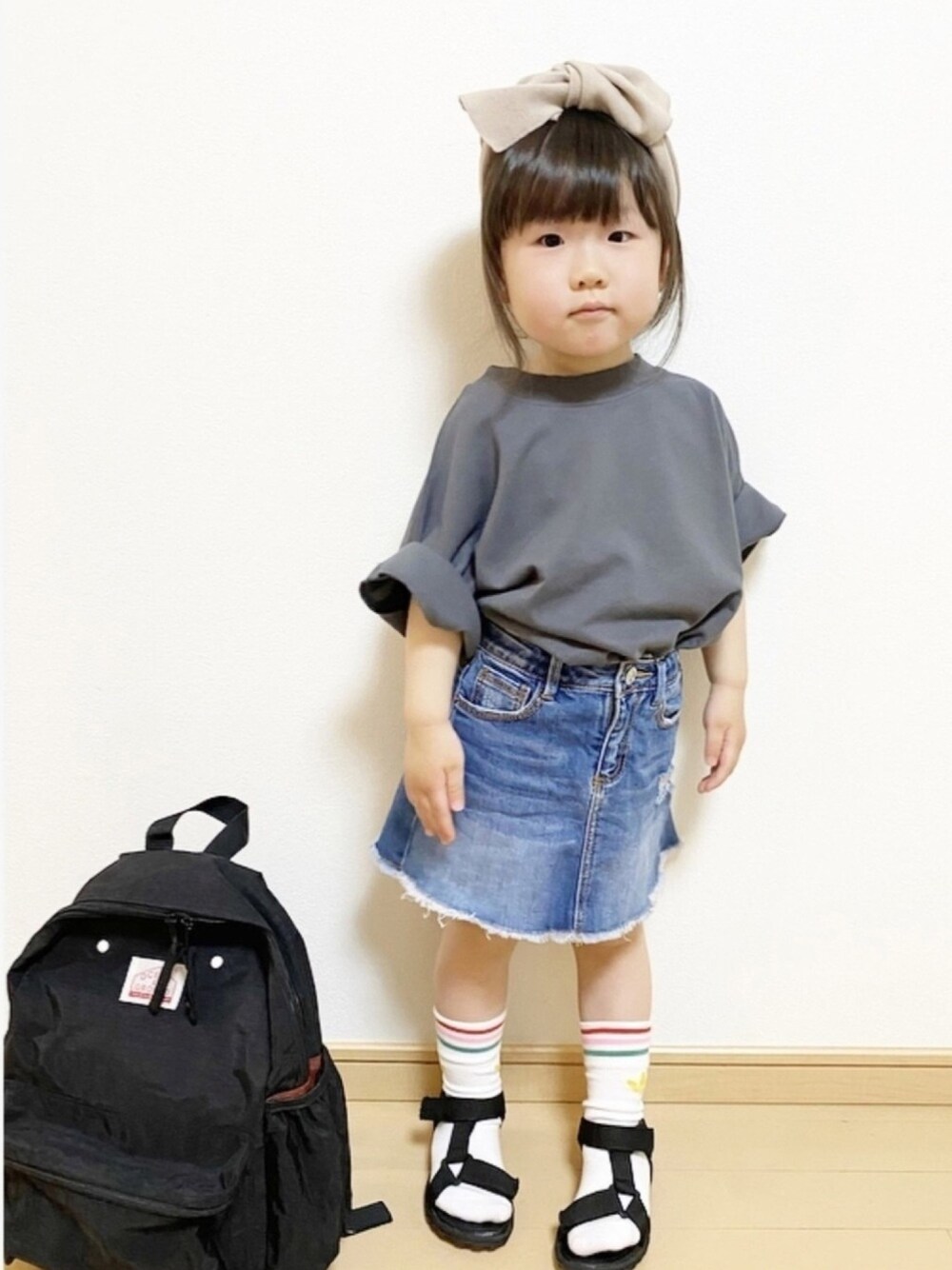 ブラック系のTシャツ/カットソー、ブルー系のデニムスカート、ブラック系のバックパック/リュックを着用したキッズの春コーディネートの1枚目の写真