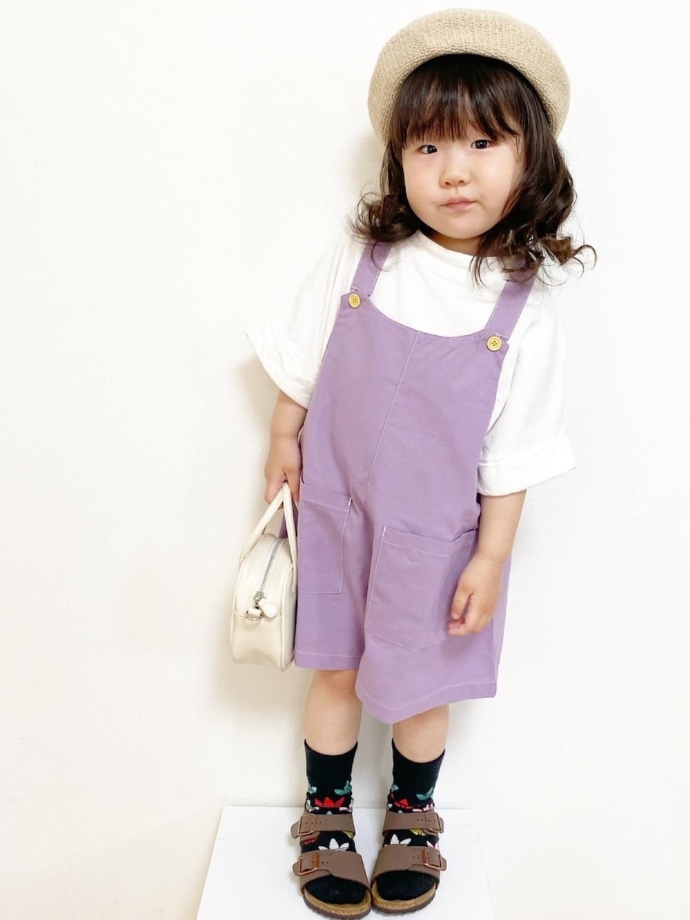 パープル系のサロペット/オーバーオール、ホワイト系のTシャツ/カットソー、ホワイト系のハンドバッグを着用したキッズの春コーディネートの1枚目の写真