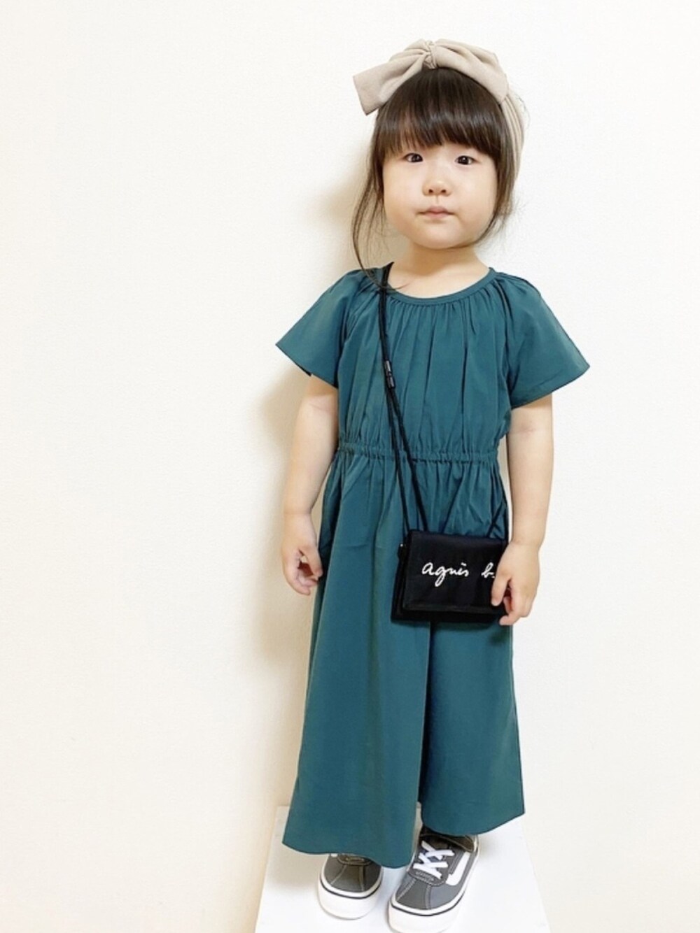 グリーン系のワンピース、グレー系のスニーカー、ホワイト系のヘアバンドを着用したキッズの夏コーディネートの1枚目の写真