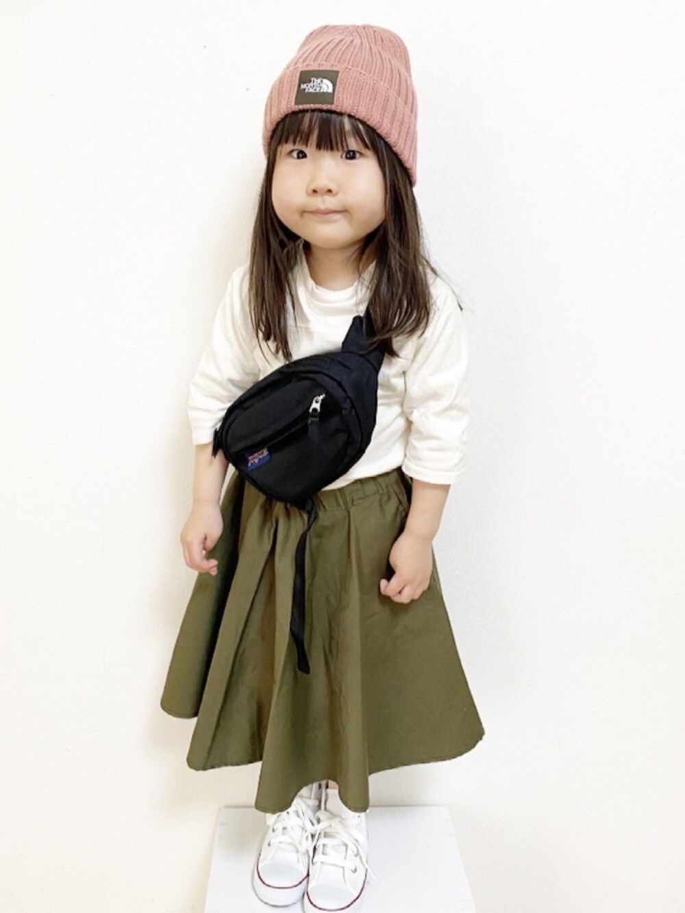 ブラック系のボディバッグ/ウエストポーチ、グリーン系のスカート、ホワイト系のスニーカーを着用したキッズの春コーディネートの1枚目の写真