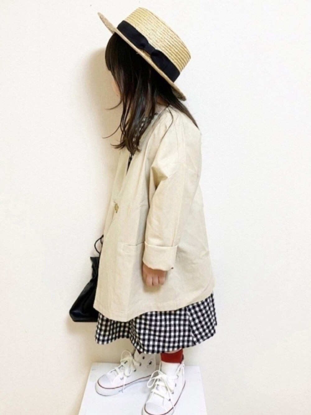 ブラック系のドレス、ベージュ系のテーラードジャケット、ブラック系のショルダーバッグを着用したキッズの春コーディネートの1枚目の写真