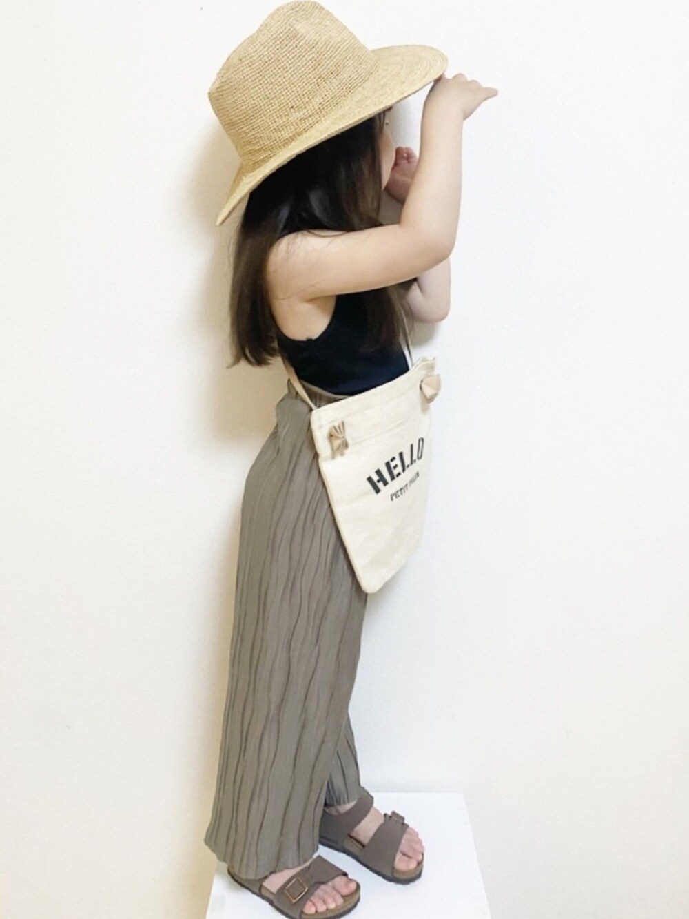 ブラック系のトップス、ホワイト系のショルダーバッグ、ブラウン系のその他パンツを着用したキッズの春コーディネートの1枚目の写真