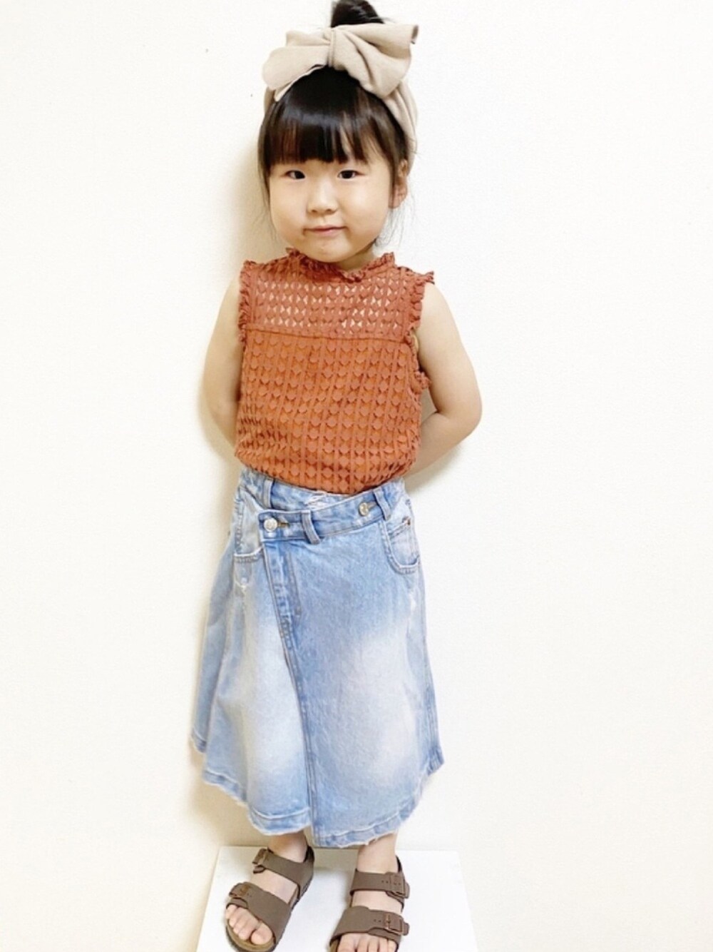 レッド系のシャツ/ブラウス、ブルー系のデニムスカート、ブラウン系のサンダルを着用したキッズの春コーディネートの1枚目の写真