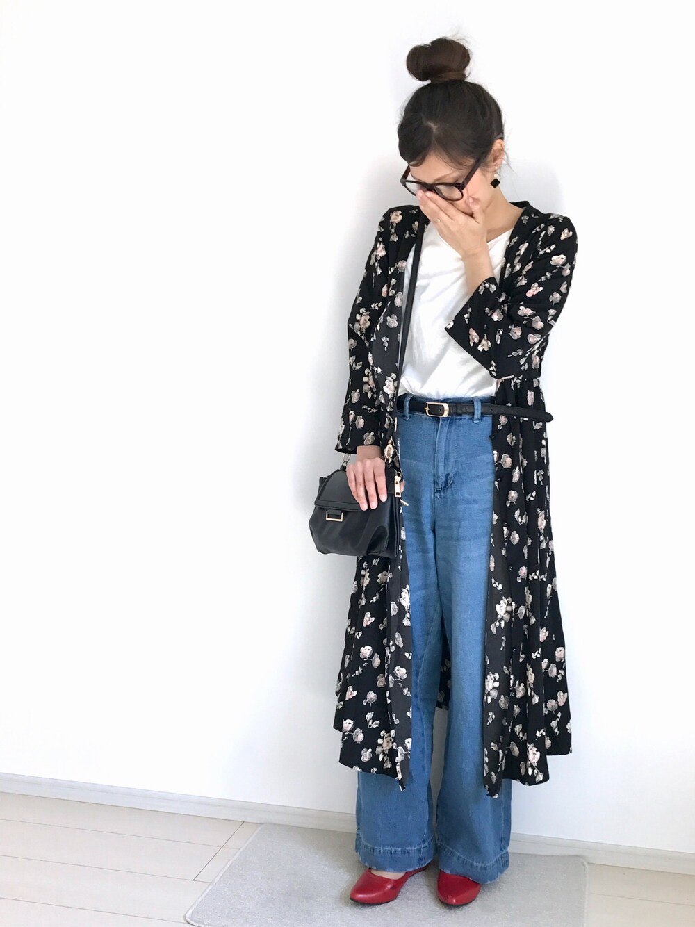 ブラック系のシャツワンピース、ホワイト系のTシャツ/カットソー、ブルー系のデニムパンツを着用したレディースの春コーディネートの1枚目の写真