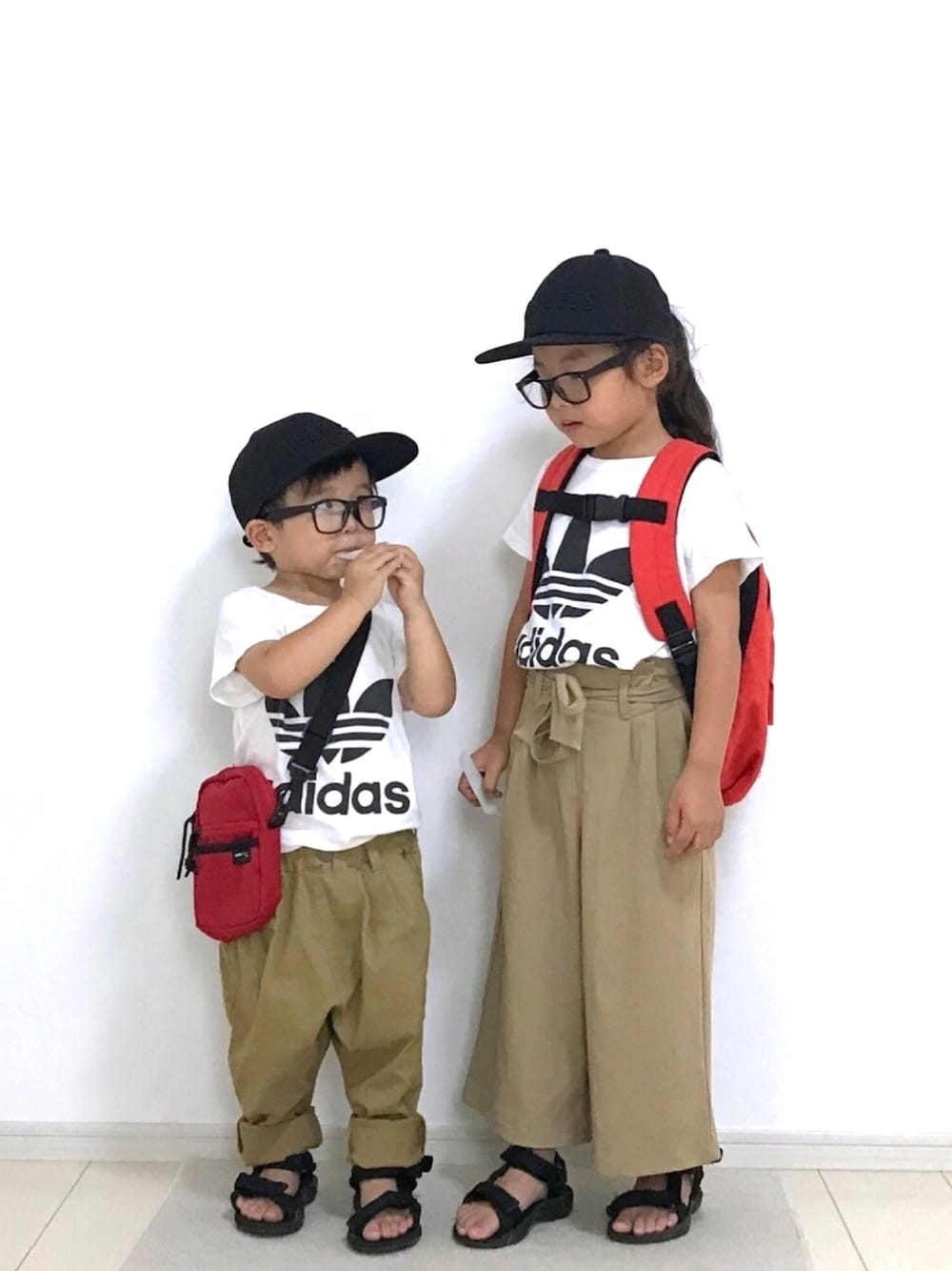 レッド系のバックパック/リュック、ベージュ系のその他パンツ、レッド系のショルダーバッグを着用したキッズの夏コーディネートの1枚目の写真