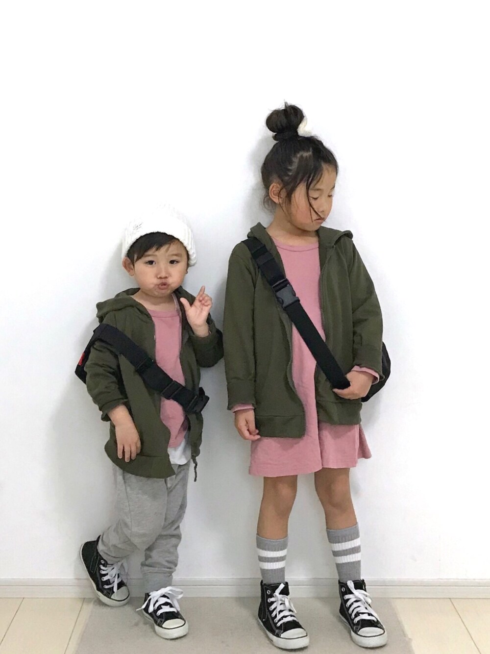 グリーン系のパーカー、ピンク系のワンピース、ブラック系のスニーカーを着用したキッズの春コーディネートの1枚目の写真