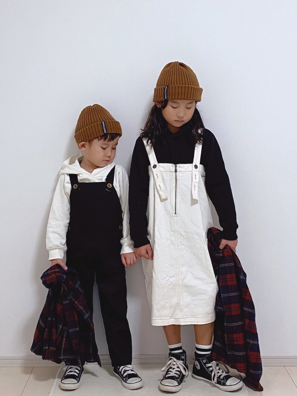 ブラック系のパーカー、ホワイト系のジャンパースカート、ブラウン系のシャツワンピースを着用したキッズの秋コーディネートの1枚目の写真