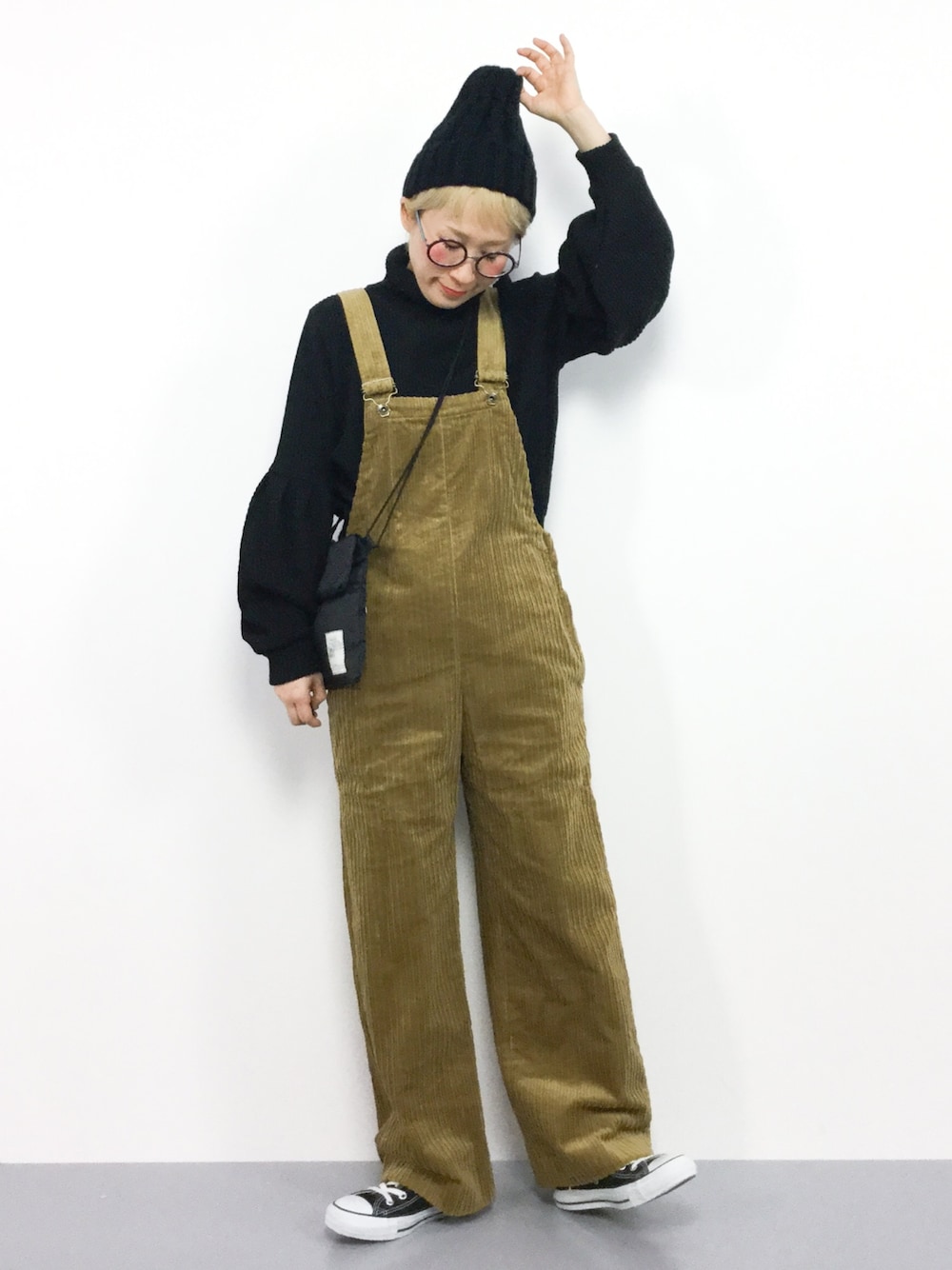 ブラック系のニット/セーター、イエロー系のサロペット/オーバーオール、ブラック系のニットキャップ/ビーニーを着用したレディースの冬コーディネートの1枚目の写真