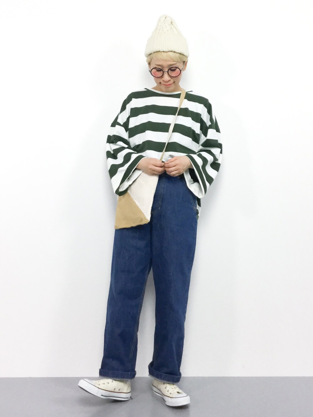 ブルー系のデニムパンツ、グリーン系のTシャツ/カットソー、ベージュ系のショルダーバッグを着用したレディースの冬コーディネートの1枚目の写真