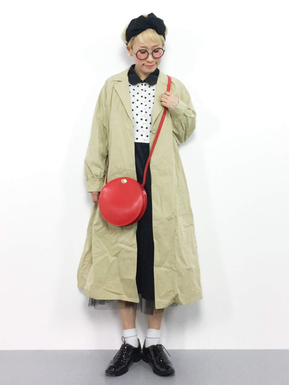 ベージュ系のチェスターコート、ホワイト系のワンピース、レッド系のショルダーバッグを着用したレディースの冬コーディネートの1枚目の写真