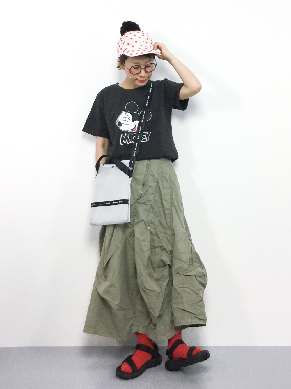 グリーン系のスカート、ホワイト系のショルダーバッグ、ブラック系のTシャツ/カットソーを着用したレディースの夏コーディネートの1枚目の写真