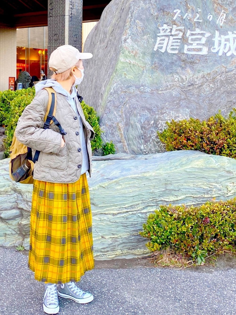 グレー系のパーカー、グリーン系のナイロンジャケット、イエロー系のその他パンツを着用したレディースの冬コーディネートの1枚目の写真