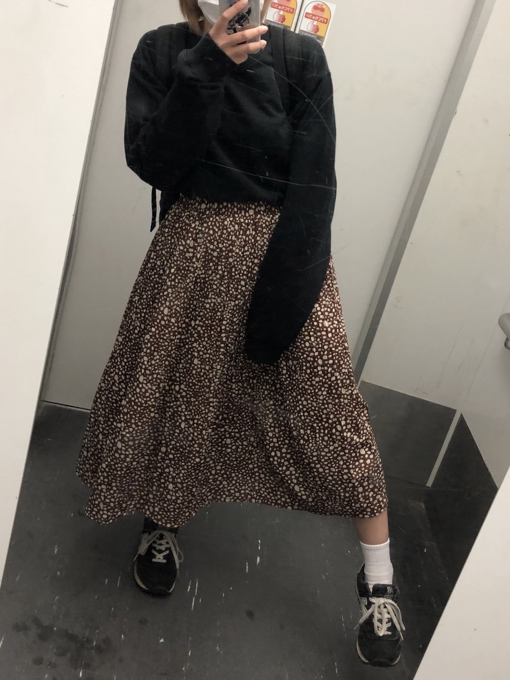 ブラック系のTシャツ/カットソー、ブラウン系のスカート、ブラック系のスニーカーを着用したレディースの秋コーディネートの1枚目の写真