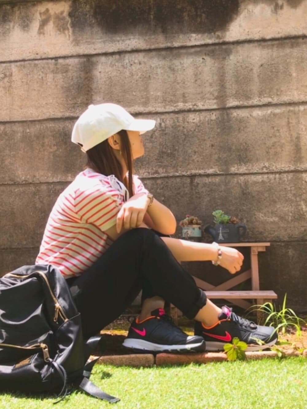 オレンジ系のTシャツ/カットソー、ブラック系のデニムパンツ、ブラック系のバックパック/リュックを着用したレディースの夏コーディネートの1枚目の写真