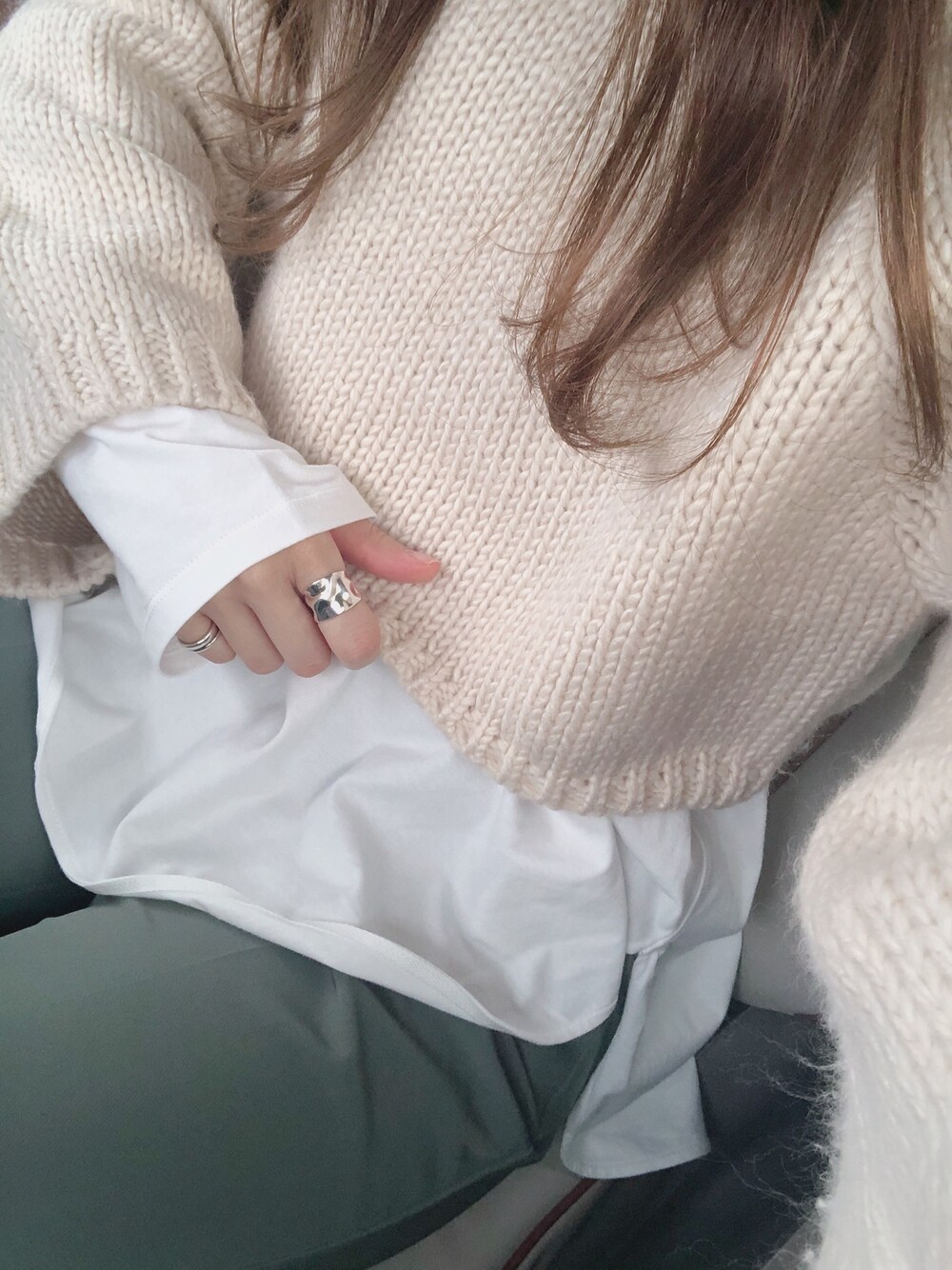 ベージュ系のニット/セーター、ホワイト系のTシャツ/カットソー、グリーン系のスラックスを着用したレディースの春コーディネートの1枚目の写真