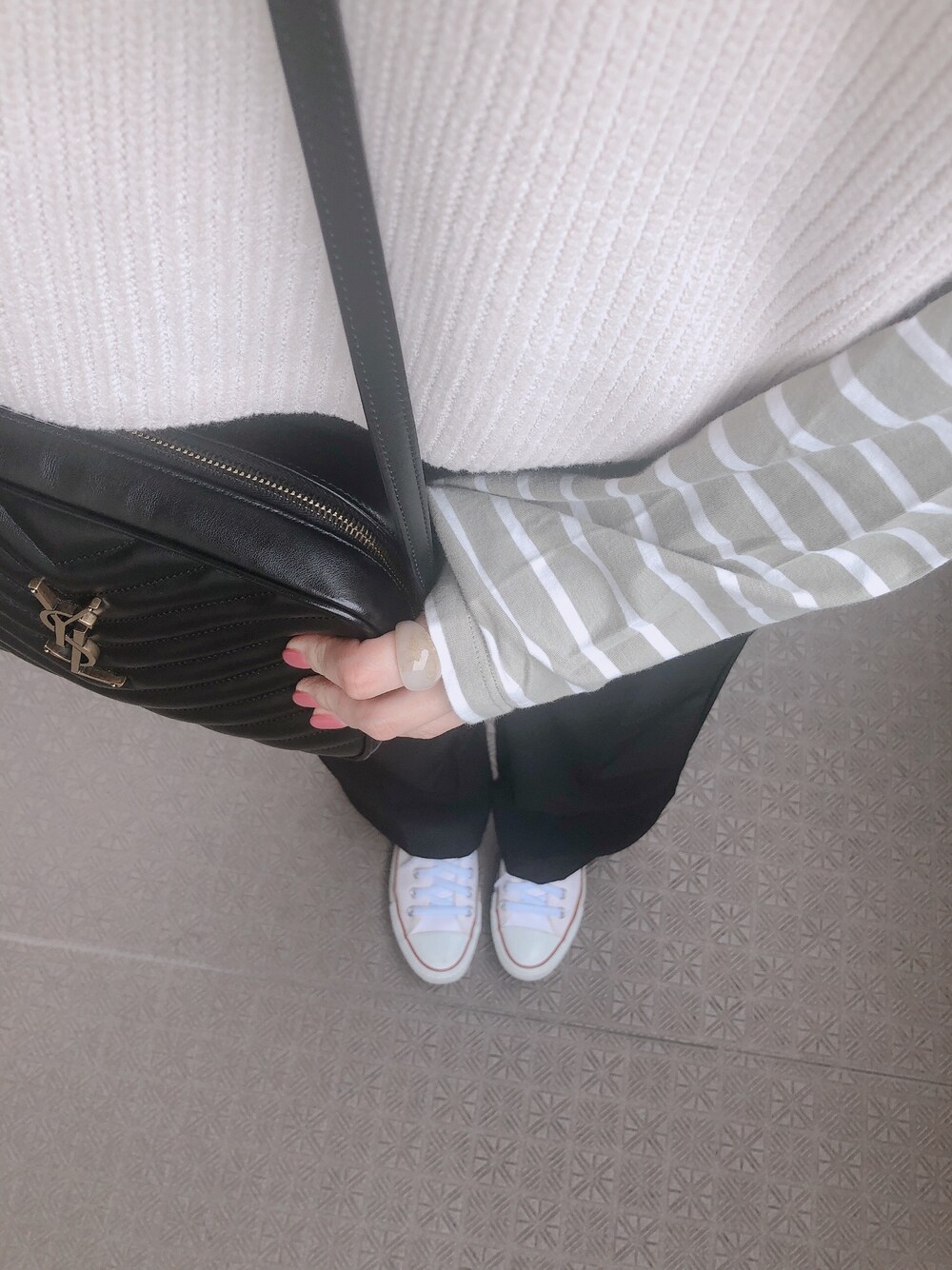 ホワイト系のベスト、ブラック系のショルダーバッグ、ブラック系のスラックスを着用したレディースの春コーディネートの1枚目の写真