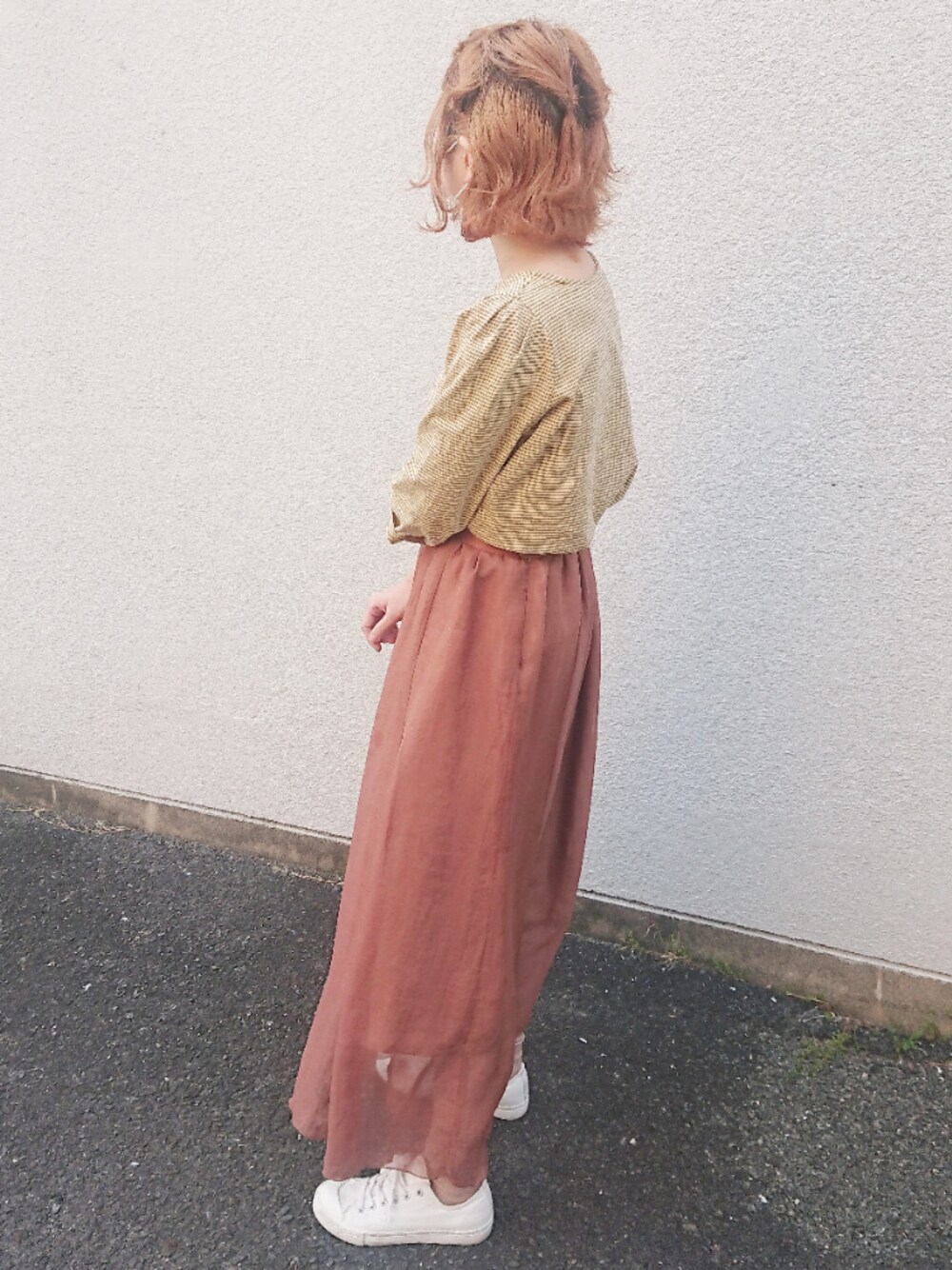 ブラウン系のスカート、イエロー系のTシャツ/カットソー、ホワイト系のスニーカーを着用したレディースの春コーディネートの1枚目の写真