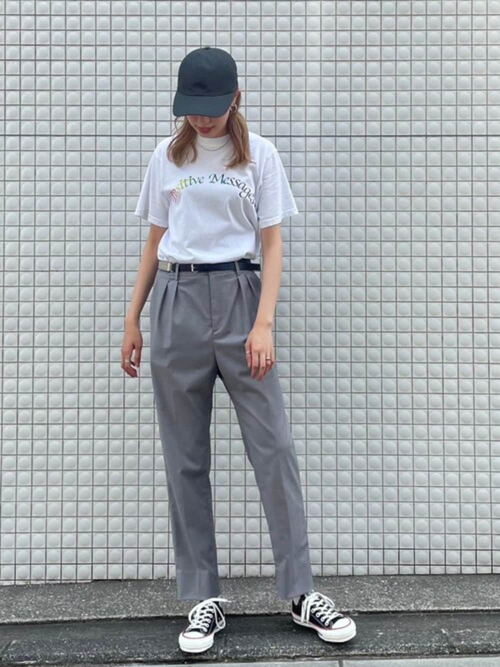 グレー系のスラックス、ブラック系のスニーカー、ブラック系のキャップを着用したレディースの春コーディネートの1枚目の写真