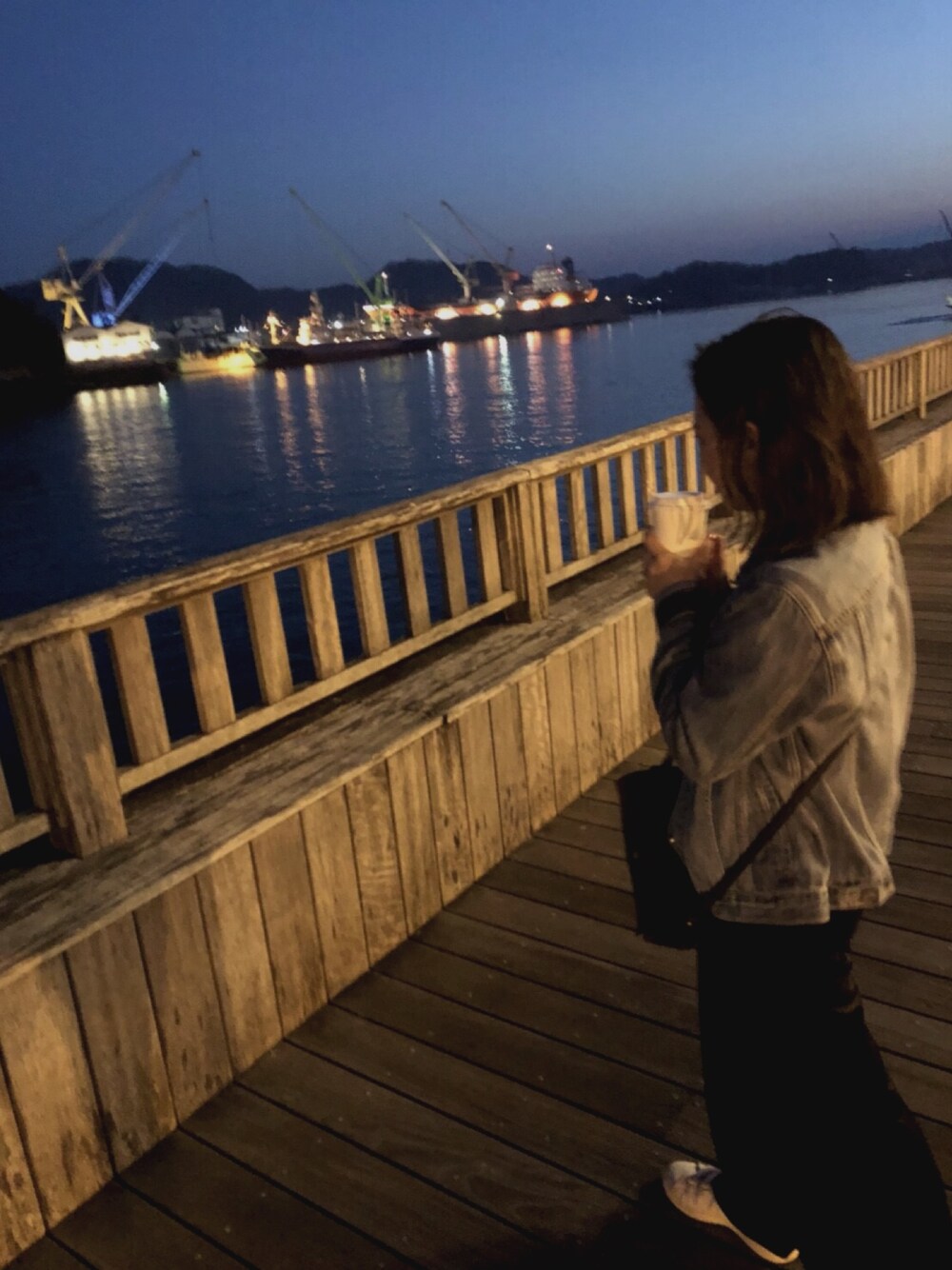 ブルー系のデニムジャケット、ブラック系のパンツ、グレー系のスニーカーを着用したレディースの春コーディネートの1枚目の写真