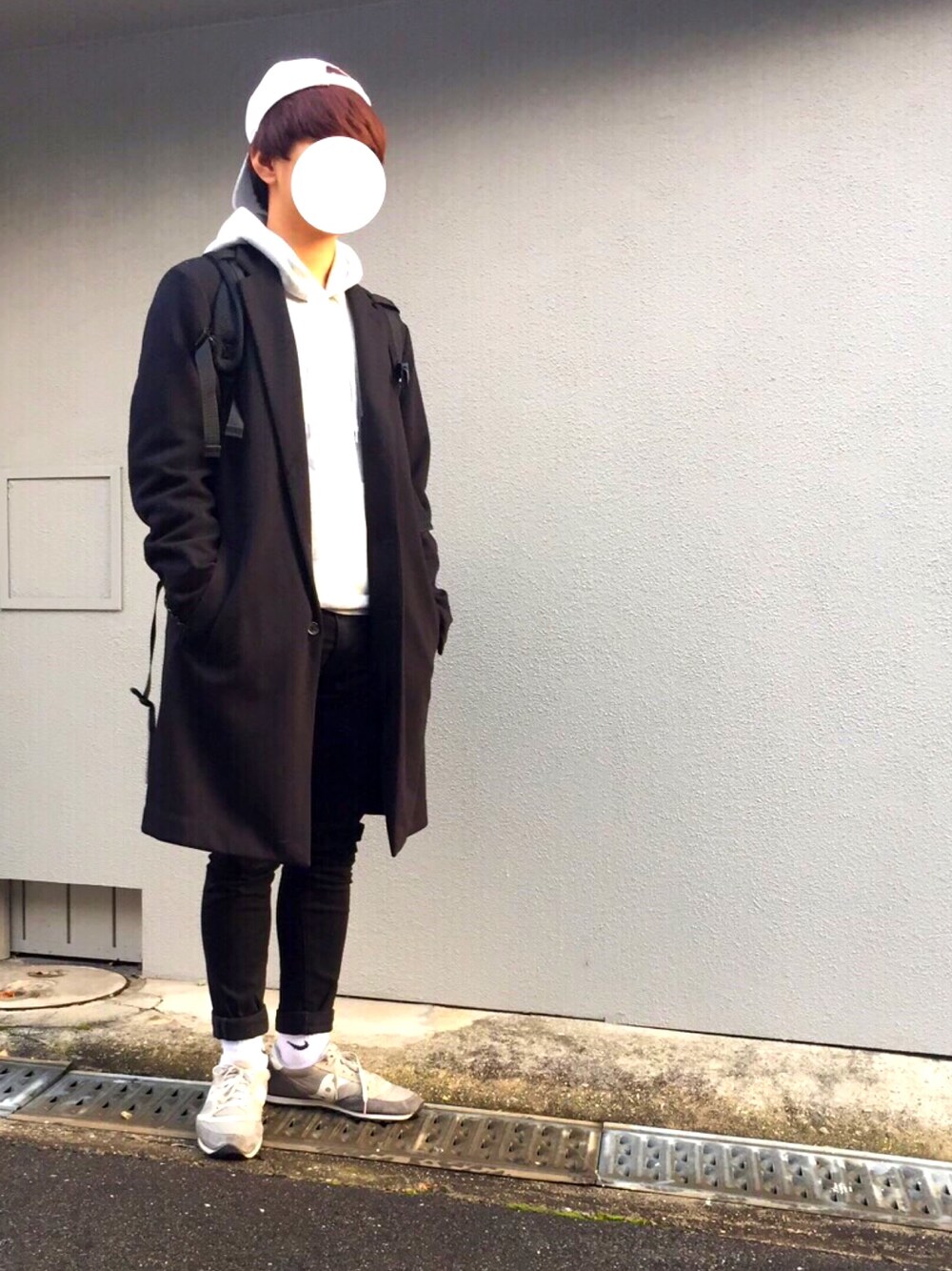 ブラック系のチェスターコート、グレー系のパーカー、ブラック系のチノパンツを着用したメンズの冬コーディネートの1枚目の写真