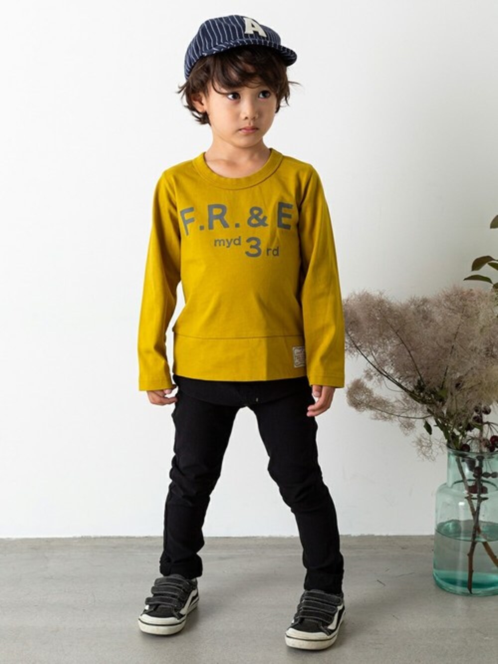 イエロー系のTシャツ/カットソー、ブラック系のその他パンツ、その他のキャップを着用したキッズの秋コーディネートの1枚目の写真