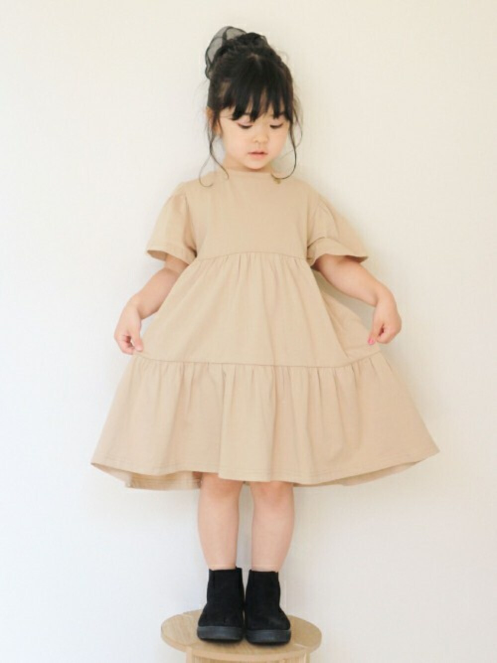 ベージュ系のワンピースを着用したキッズの春コーディネートの1枚目の写真