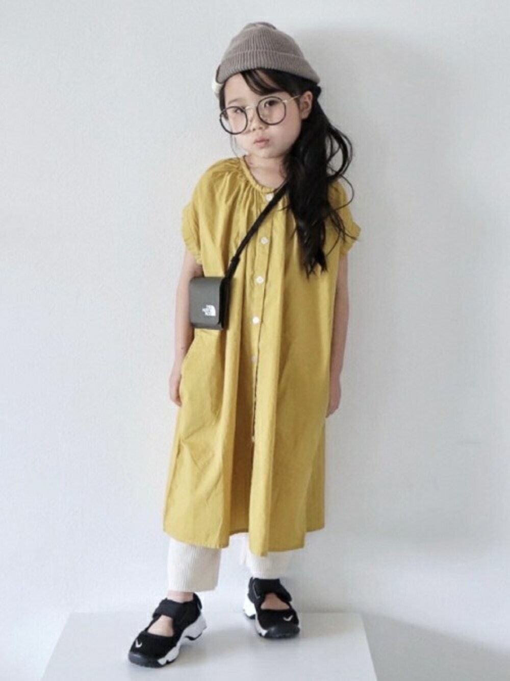 イエロー系のシャツワンピースを着用したキッズの春コーディネートの1枚目の写真